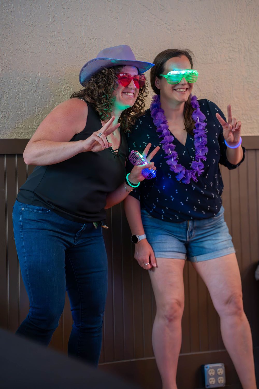 People dancing with glowing accessories and purple leis at a party.
