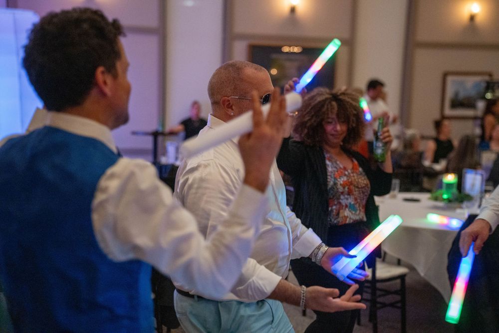 People holding glowing blue lightsabers during an indoor event celebration.
