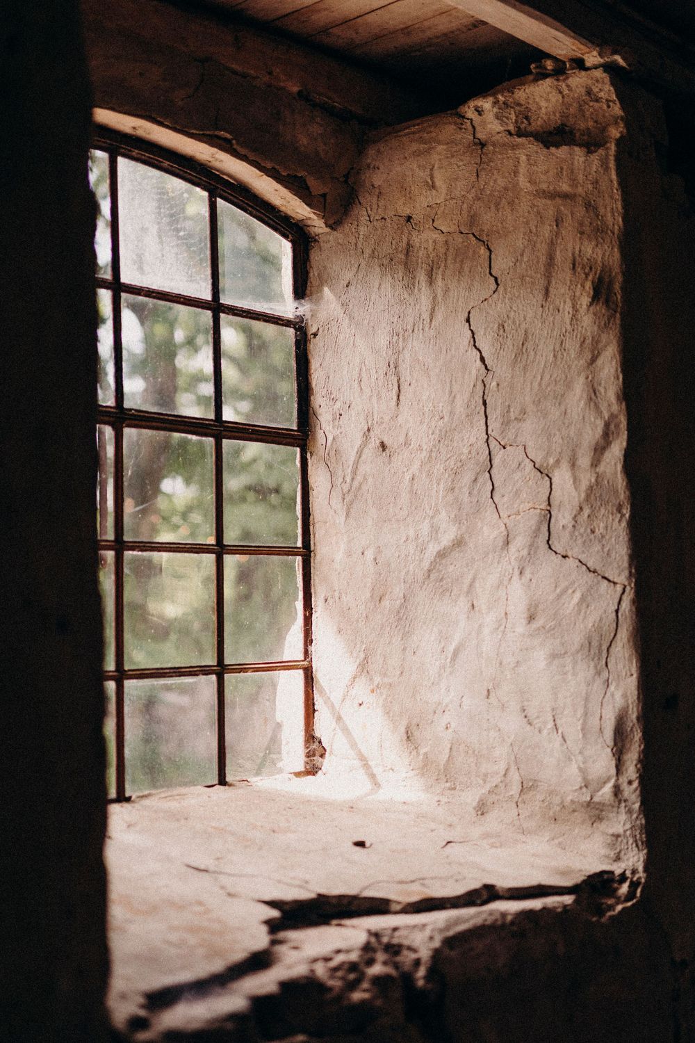 A sequence of four photographs showing a rustic window opening in an old stone or earthen wall with natural light filtering in.