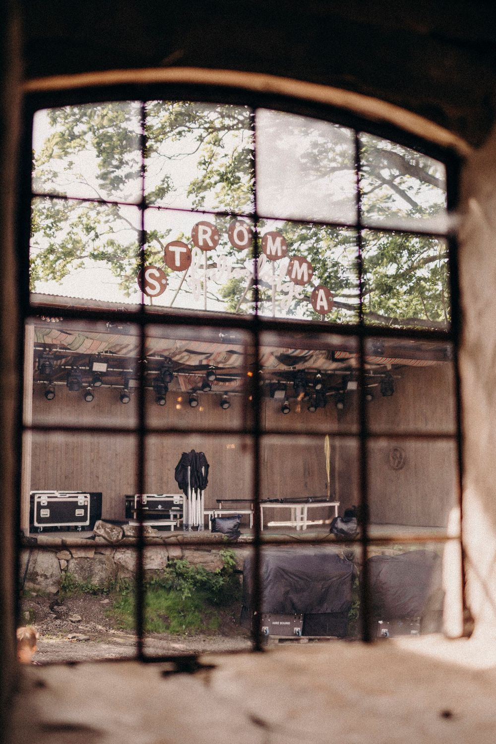 View through arched window of abandoned storefront with rustic 'STORE' lettering and exposed wooden beams.