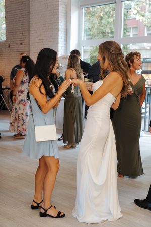 Guests dancing and mingling at a wedding reception, with the bride in a white gown and guests in formal attire.
