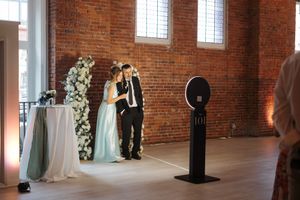 Wedding ceremony setup inside rustic brick venue with string lights and white floral arrangements creating elegant atmosphere.