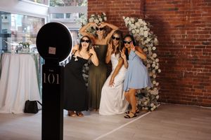 Wedding guests dancing and celebrating on a dance floor at an indoor venue with exposed brick walls.