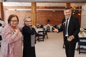 Family and friends celebrate together at a reception in a rustic brick-walled venue with warm lighting and elegant decor.