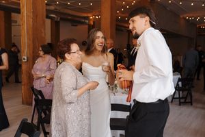 A couple dances together at a wedding reception under string lights in an elegant indoor venue.