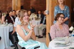 Wedding guests seated at rustic wooden tables during an elegant barn reception celebration.