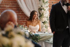 A couple sits together at their reception table adorned with delicate floral arrangements and candlelight decor.