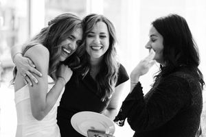 Three friends share a joyous candid moment laughing together in black and white photograph.