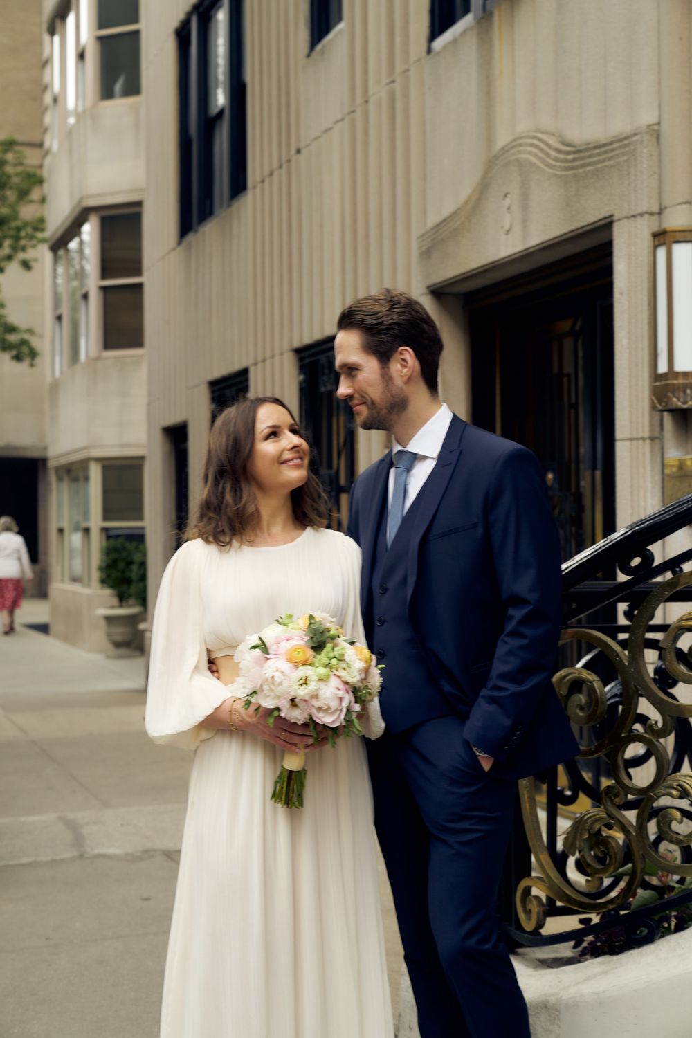 Newlywed couple sharing intimate moments in formal attire by classic architecture columns at their wedding. Wedding photoshoot