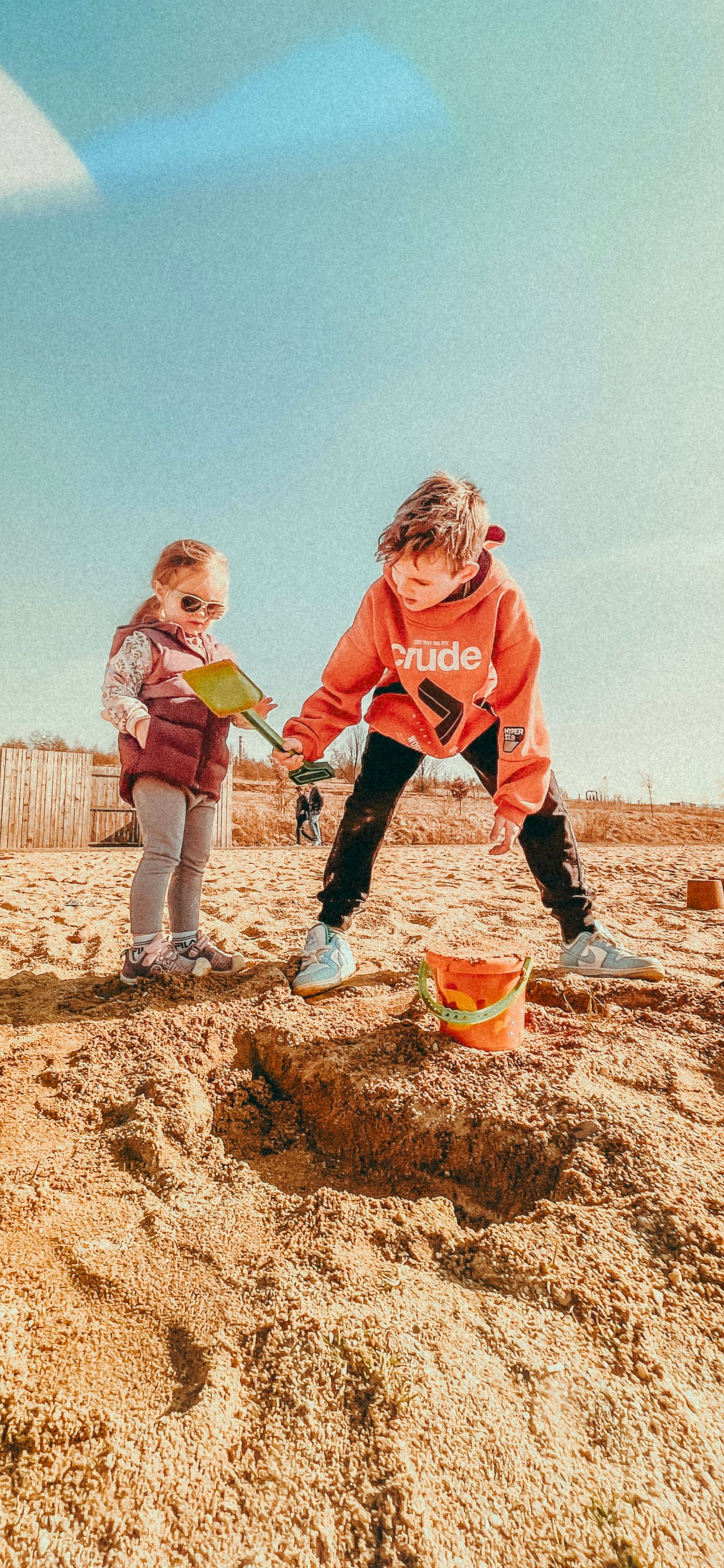 Progressive shots of a child playing in sand on a sunny beach wearing an orange jacket.