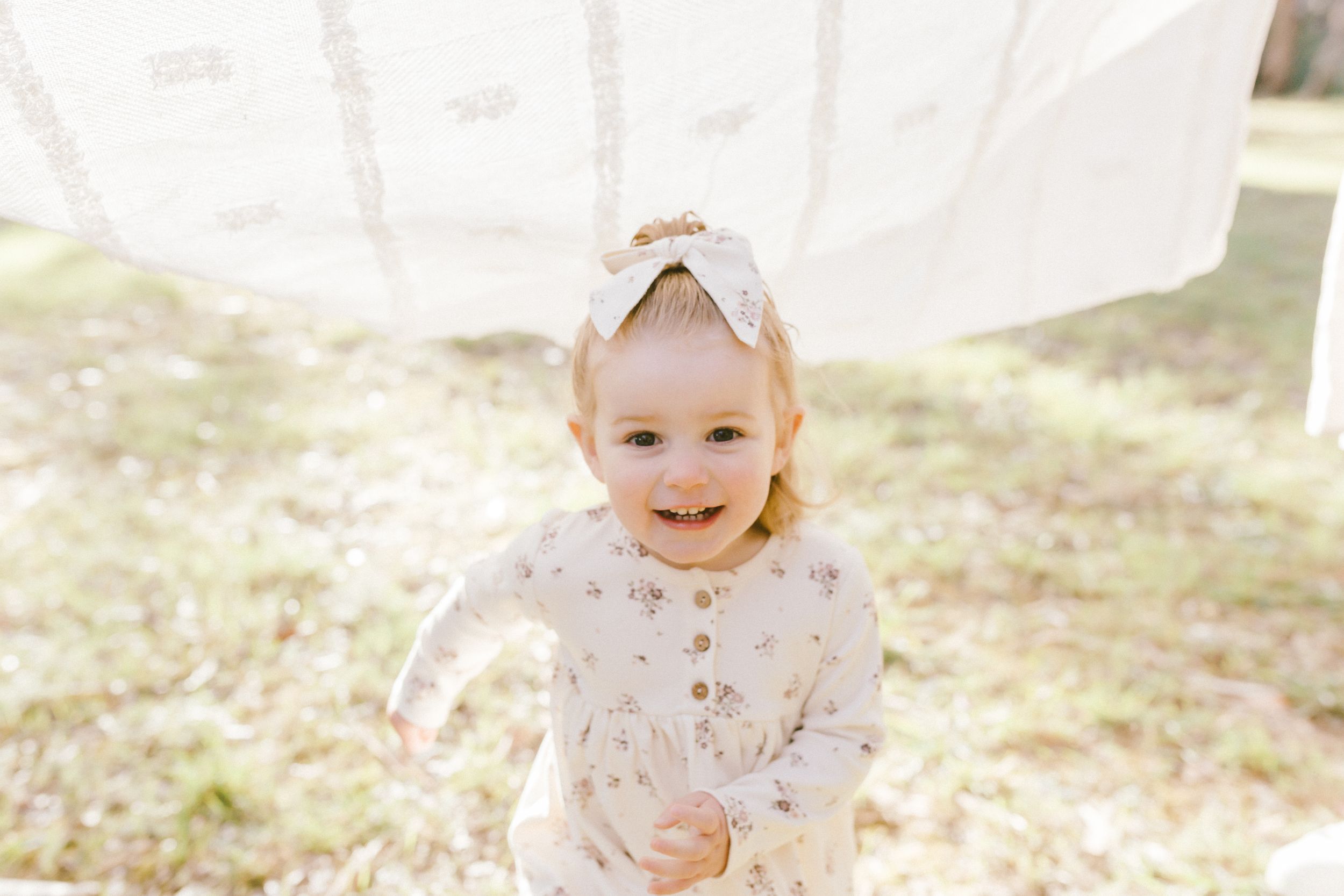 People dressed in white enjoying a playful outdoor photo session in soft natural light.
