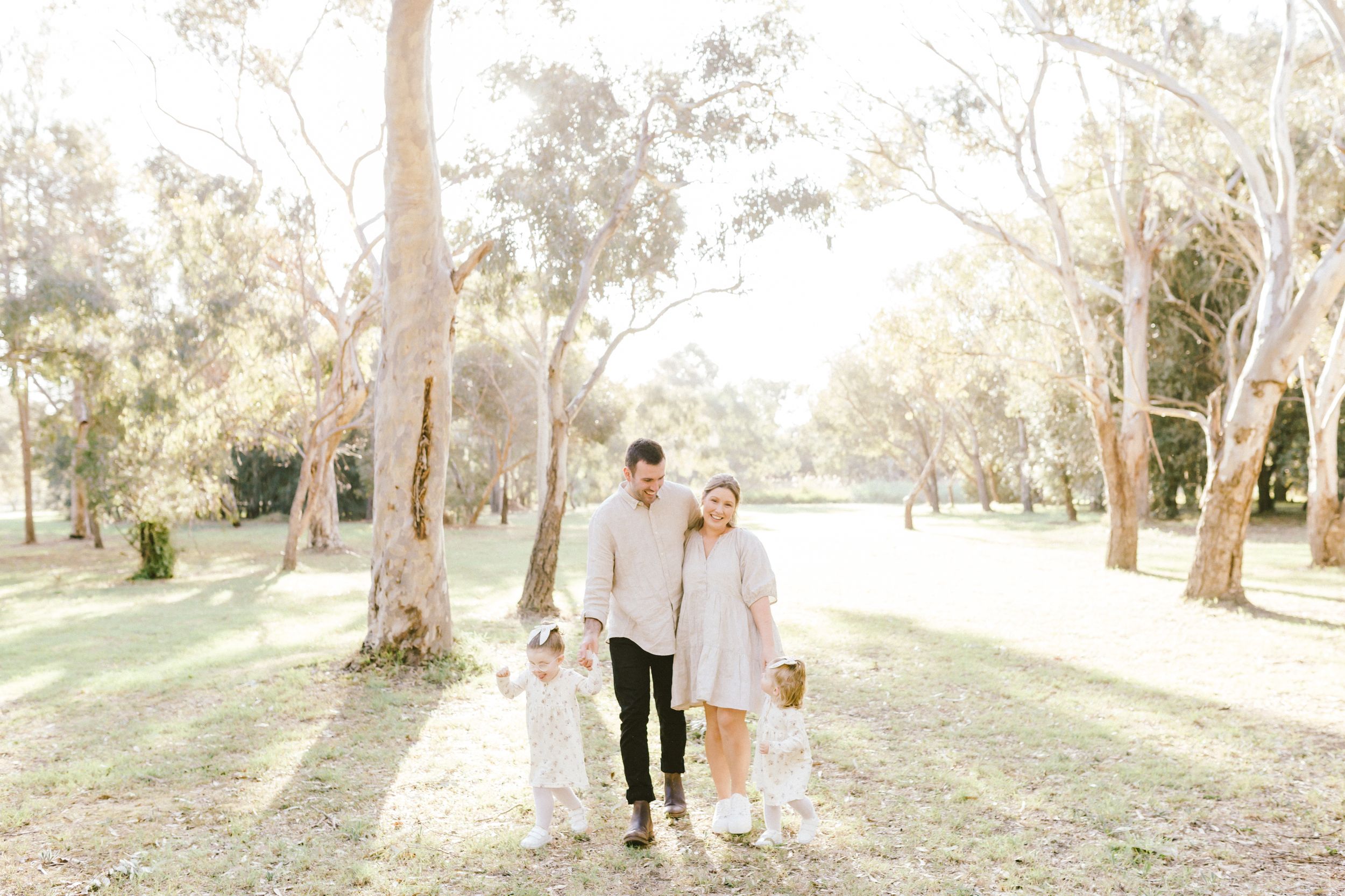 Happy family moment captured during a golden hour photoshoot in a wooded park setting.