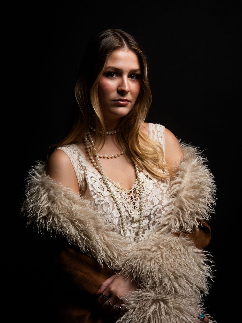 Fashion portrait with feathered white dress and dramatic lighting against dark background.