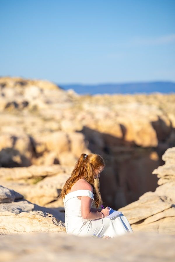 Someone laying on coastal rocks while looking at ocean views during golden hour against blue sky background.