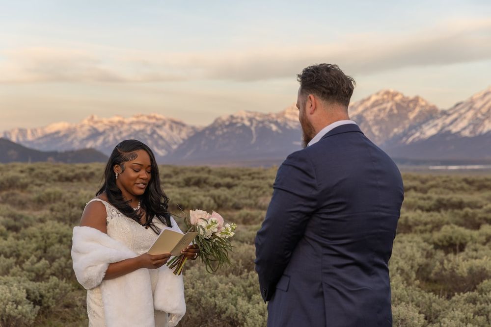 A couple shares a romantic moment in front of snow-capped mountains during an outdoor photo session.