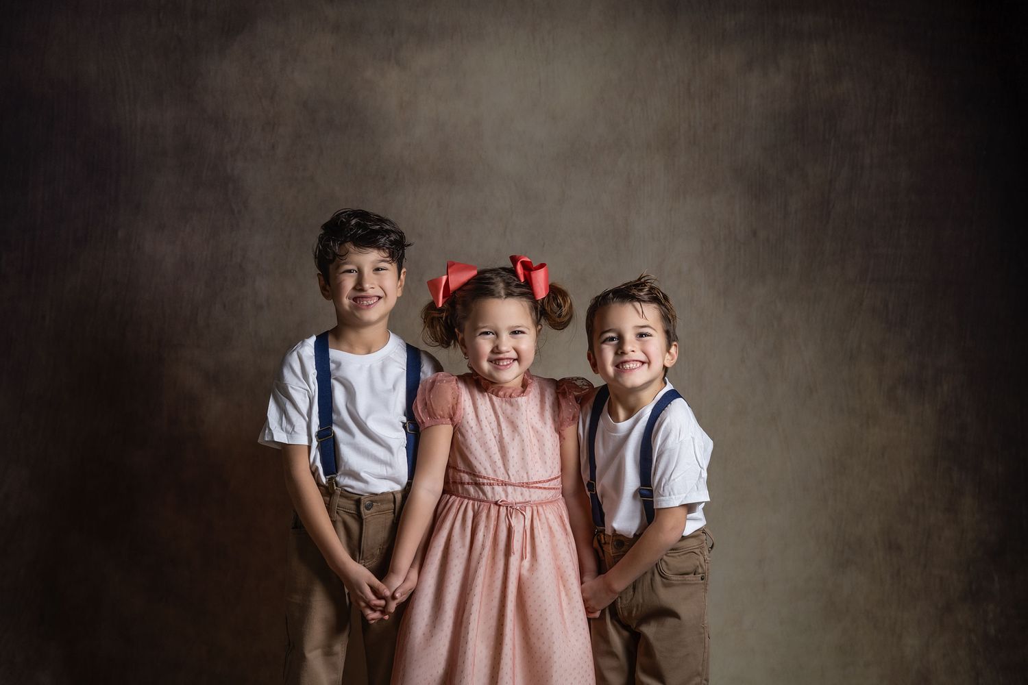Vintage style studio portraits showing three children against a textured dark gray backdrop in various poses.