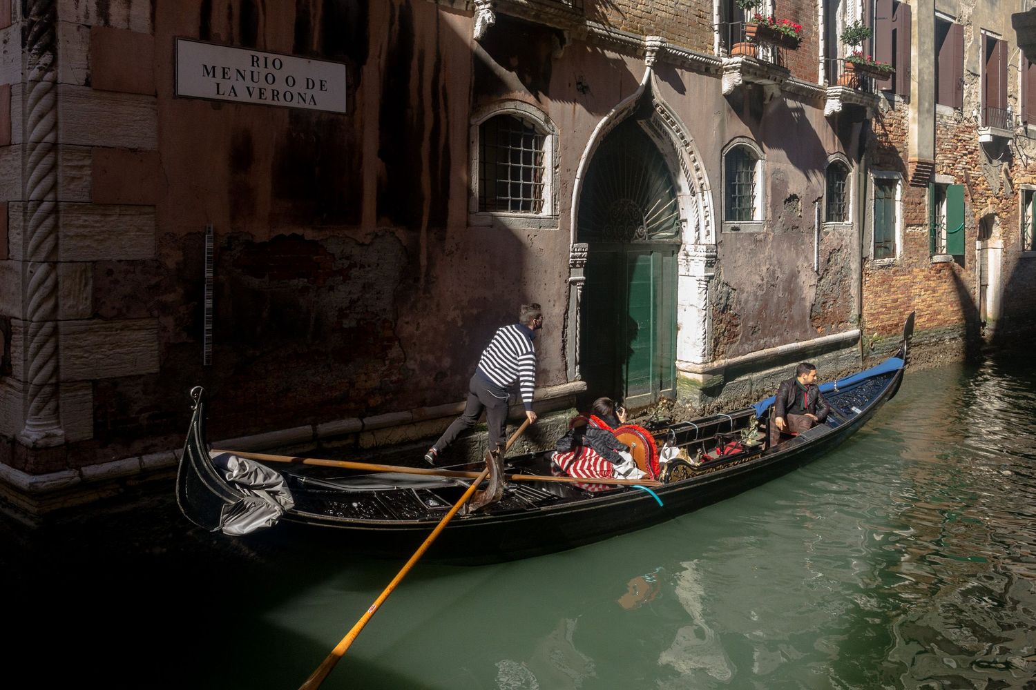 Traditional gondolas navigate through narrow canals between historic buildings in Venice, Italy.