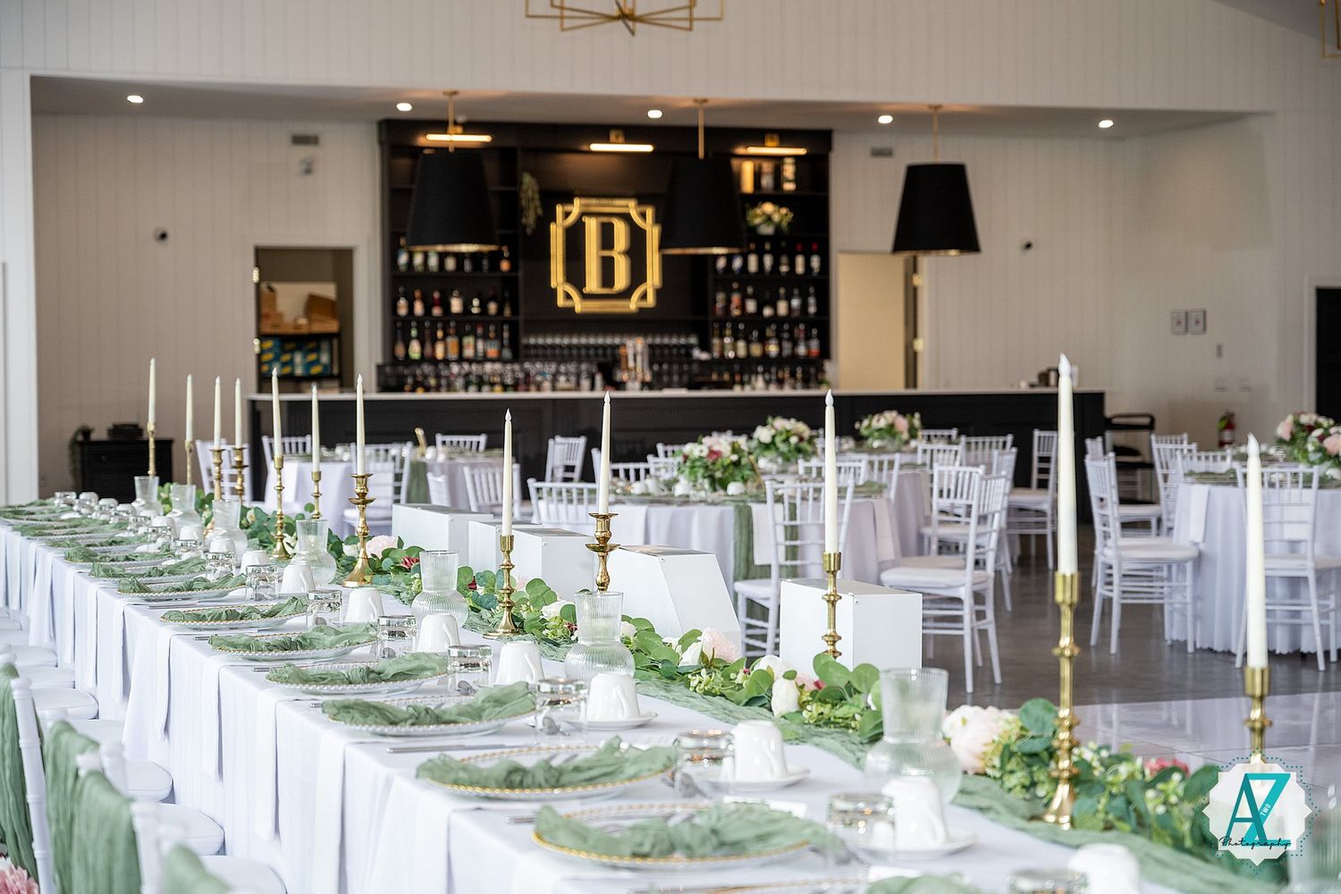 Elegant wedding reception setup with white tables and floral centerpieces in a spacious banquet hall.