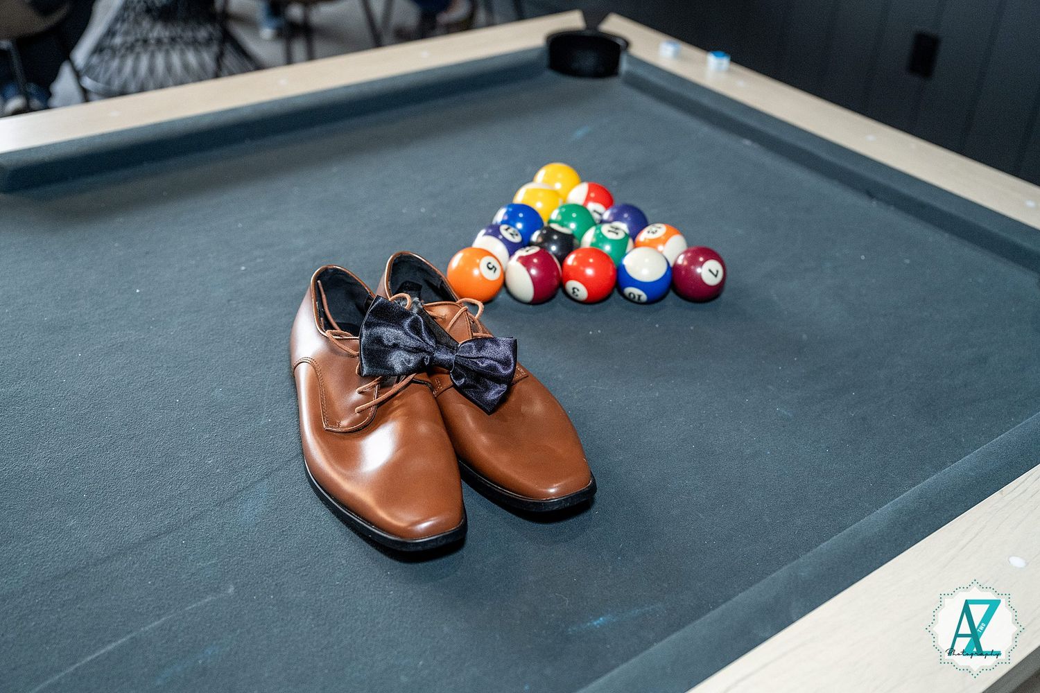 Leather dress shoes arranged on a dark surface with colorful billiard balls scattered nearby.