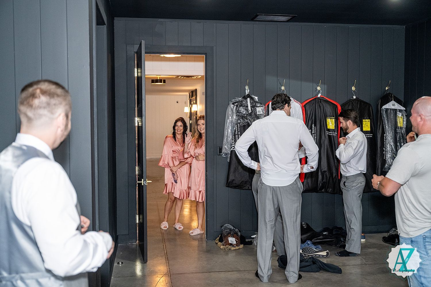 A group of people dancing and moving in front of a grey wall in what appears to be a social gathering or dance event.