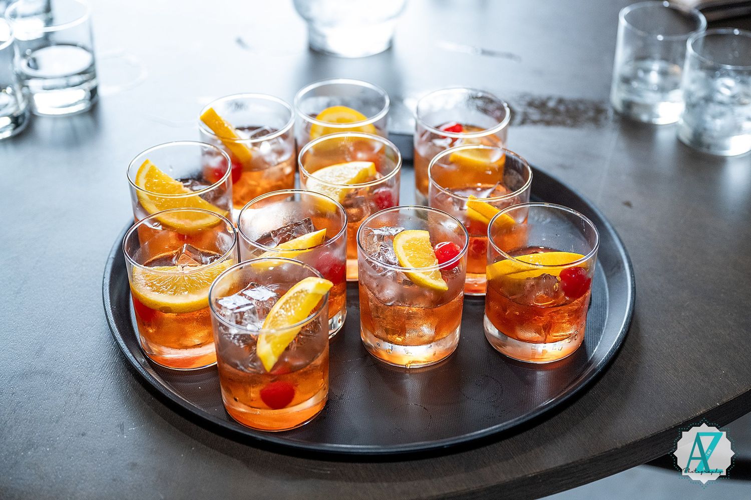 Glasses of Aperol Spritz cocktails garnished with orange slices arranged elegantly on dark serving trays.