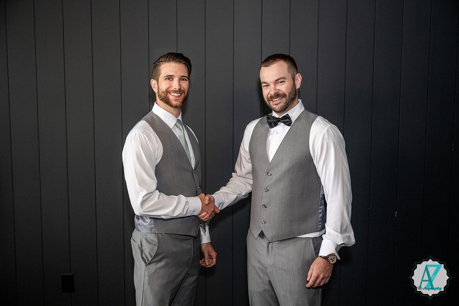 Two people in formal grey and white attire shaking hands in a professional setting.