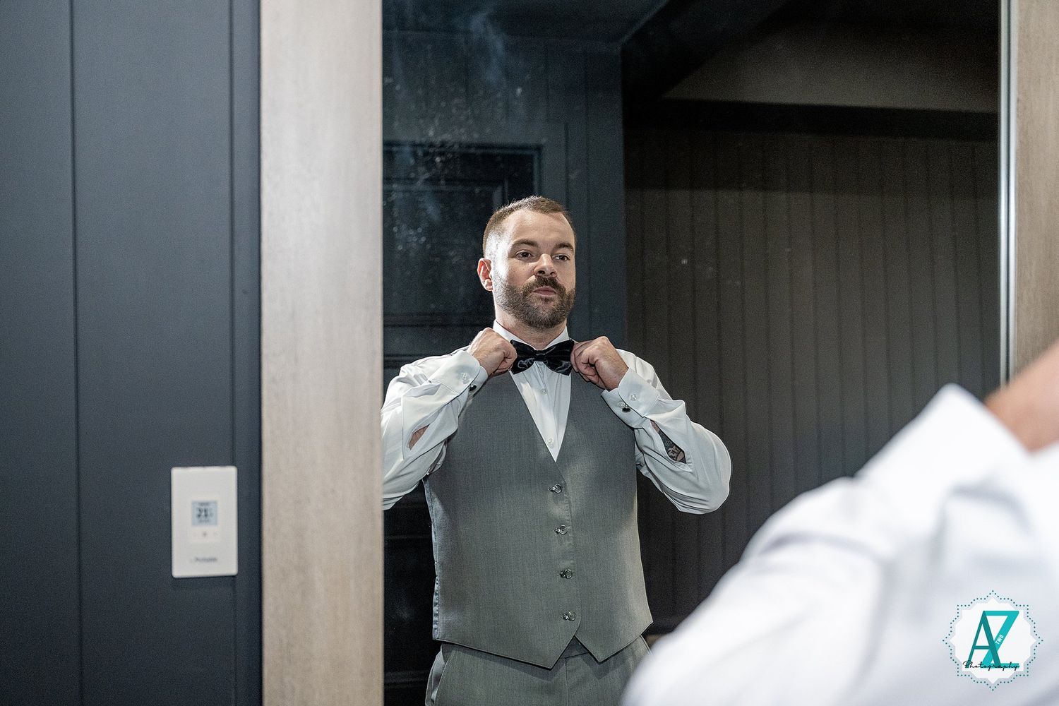 A series of people in formal attire preparing for a wedding ceremony in front of grey doorways.