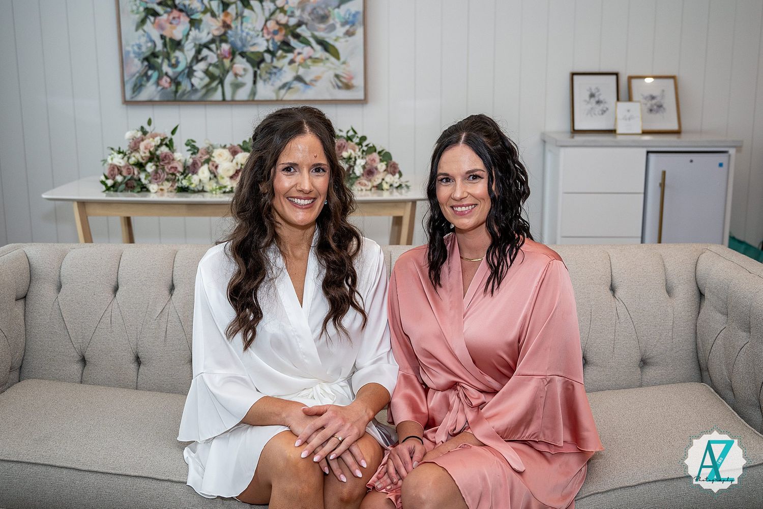 Candid series of two women sitting together on a beige couch in casual attire with floral artwork in background.