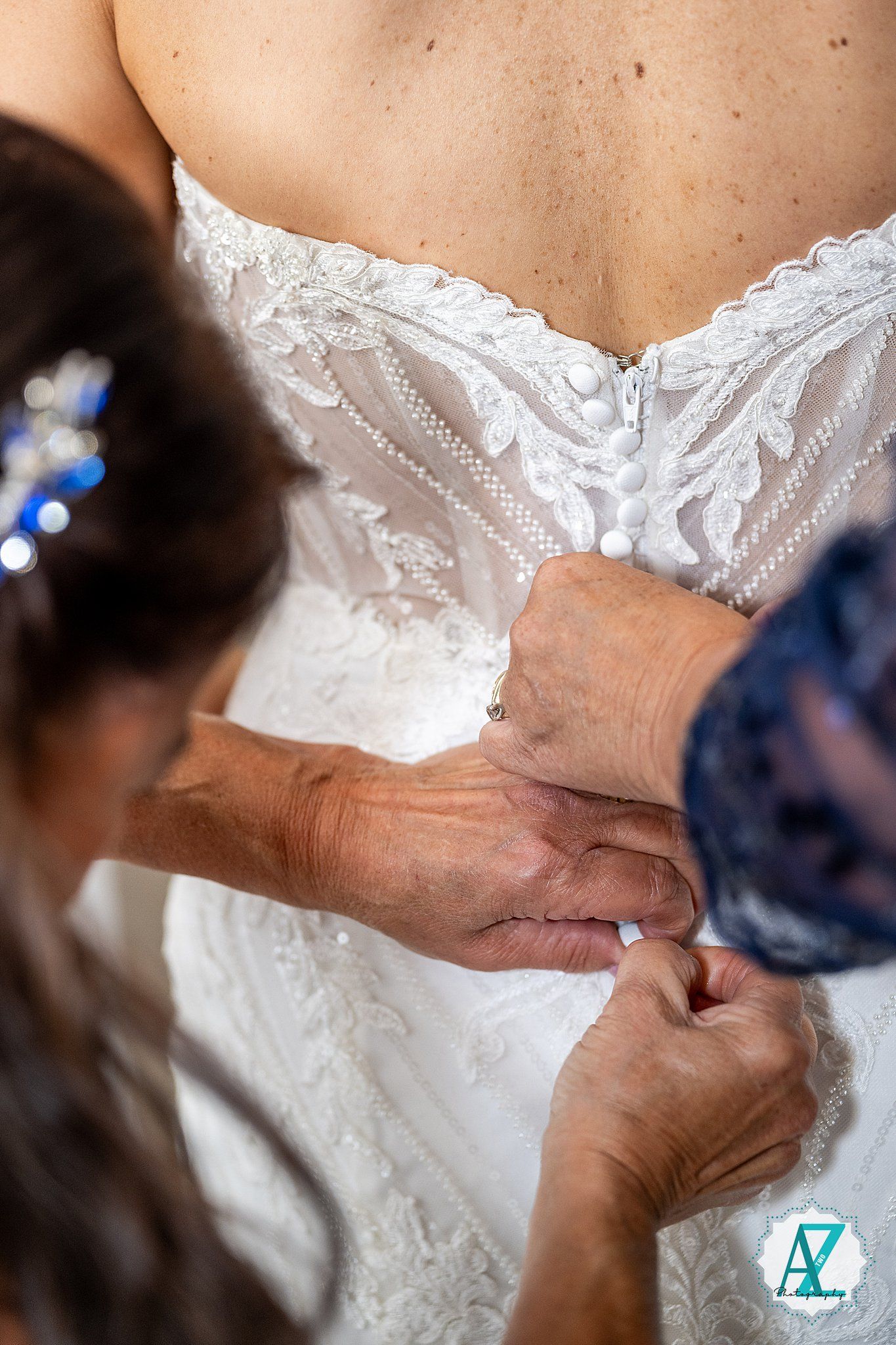 Close-up view of delicate white lace details being adjusted on a wedding dress bodice with intricate floral patterns.