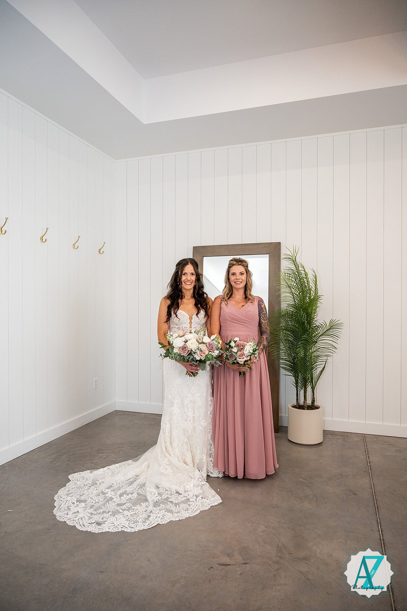 Wedding party photo shoot in a bright white room with wood paneling and potted palm plant decor.