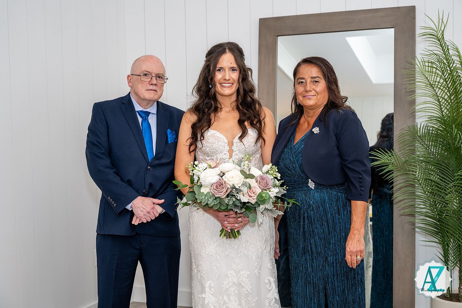 A formal wedding group wearing navy blue and white attire poses together at an indoor venue.