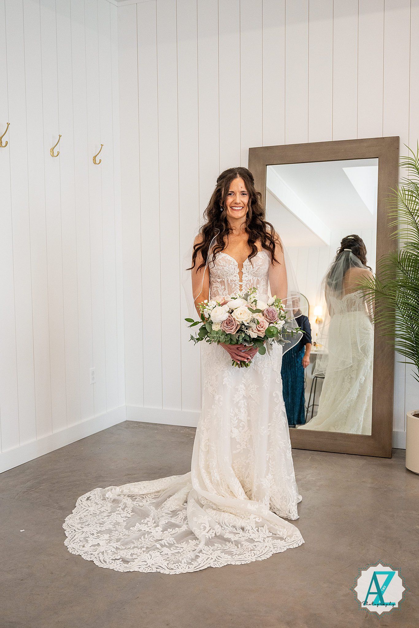 Beautiful lace wedding dress with flowing train displayed in a modern minimalist studio space.