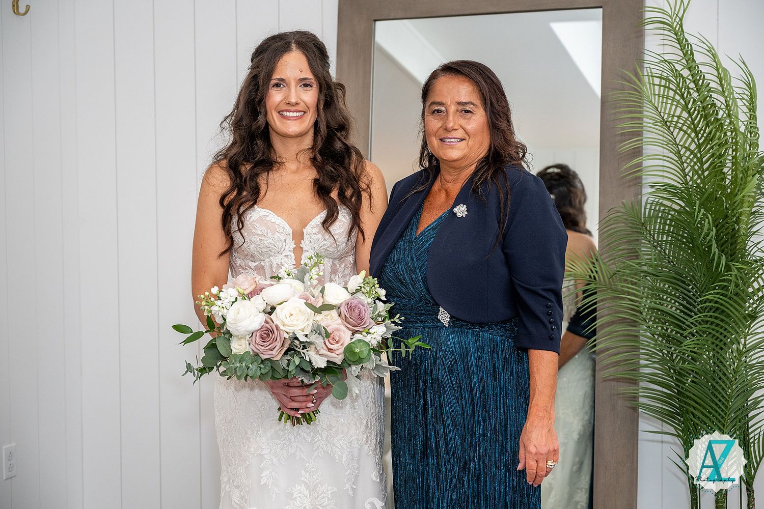 A formal wedding photo features people in navy blue and white attire standing together indoors.