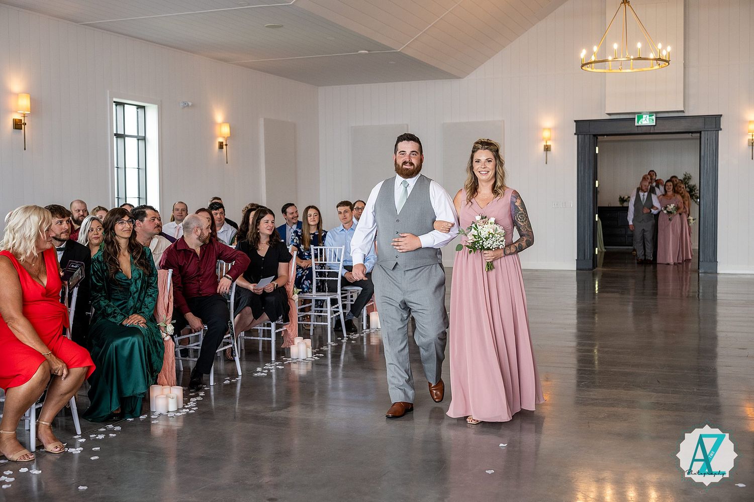 Panoramic view of a modern wedding venue with white chairs and wall sconces.