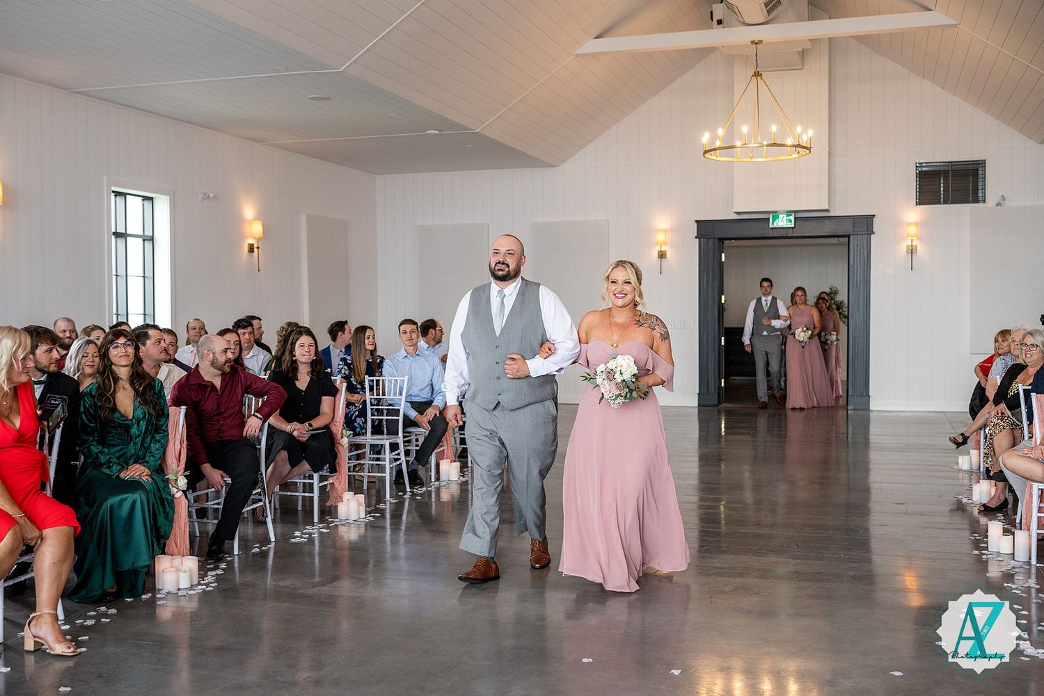 Elegant reception venue with white walls and chandeliers where guests gather for a wedding celebration.