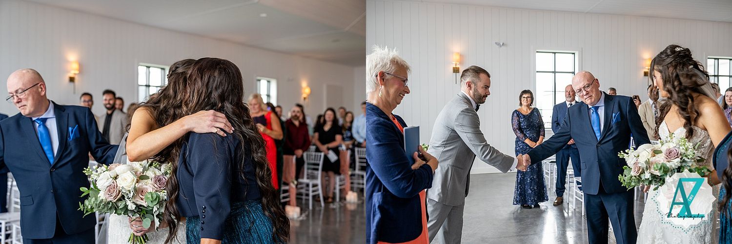 Guests stand in an elegant white venue decorated with pink accents and floor-to-ceiling windows during a wedding ceremony.