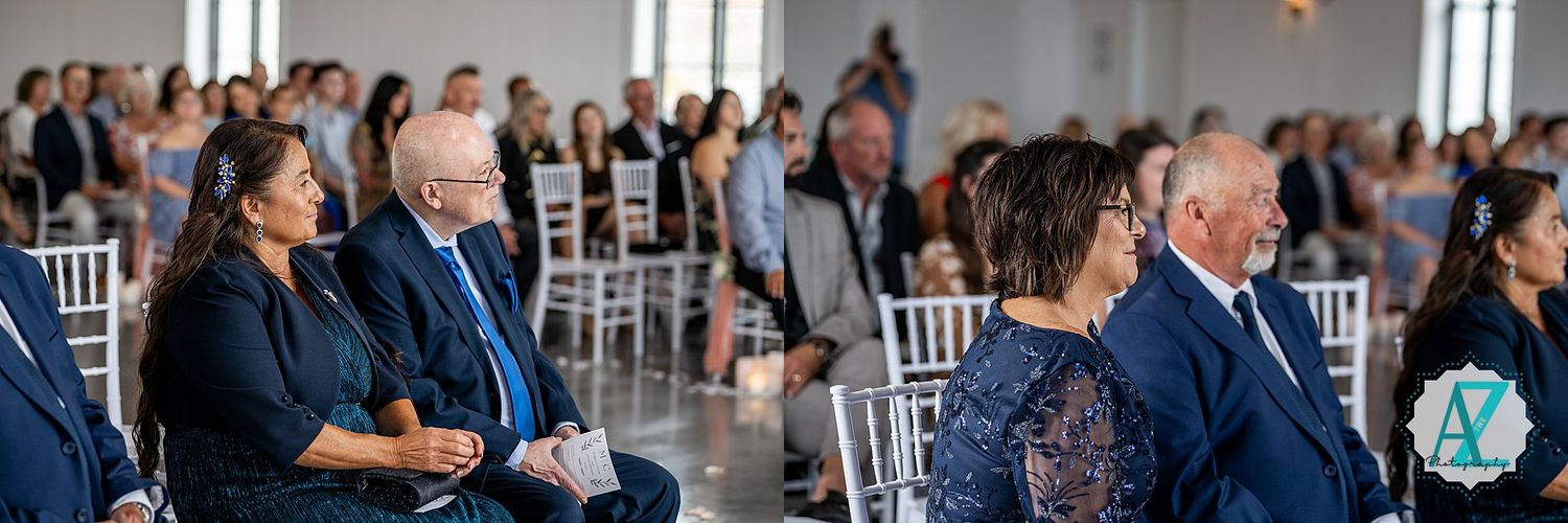 Wedding ceremony guests seated in white chairs inside an elegant venue space with natural lighting.