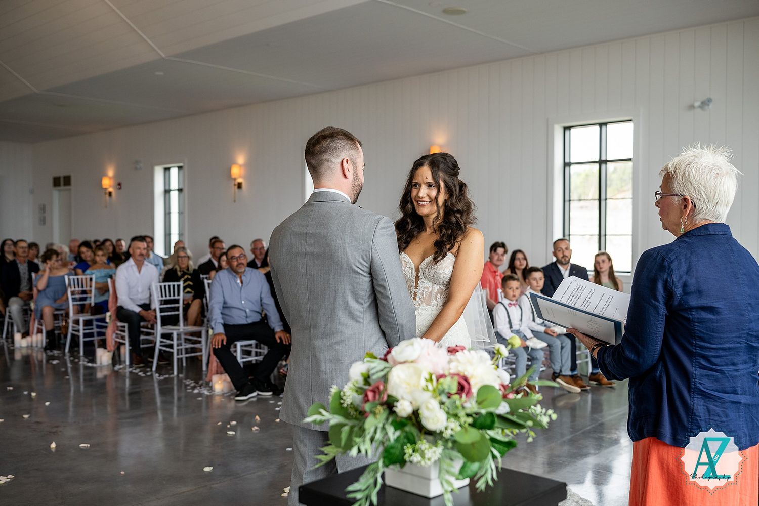 Wedding celebration in a modern white venue with natural lighting streaming through large windows.