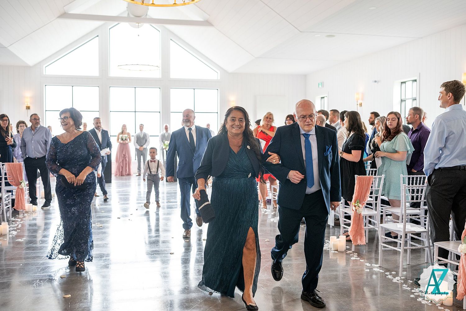 A panoramic shot of a modern sunlit venue hosting a celebratory gathering with guests mingling in formal attire.