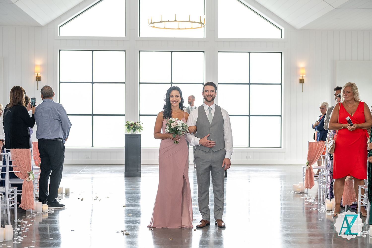 View of a bright white reception venue with vaulted ceilings and guests gathering for an elegant event.