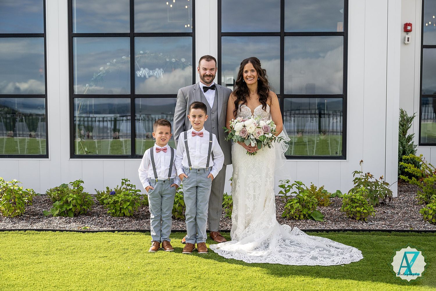 Wedding photography session with bridal party on grassy lawn in front of contemporary building exterior.