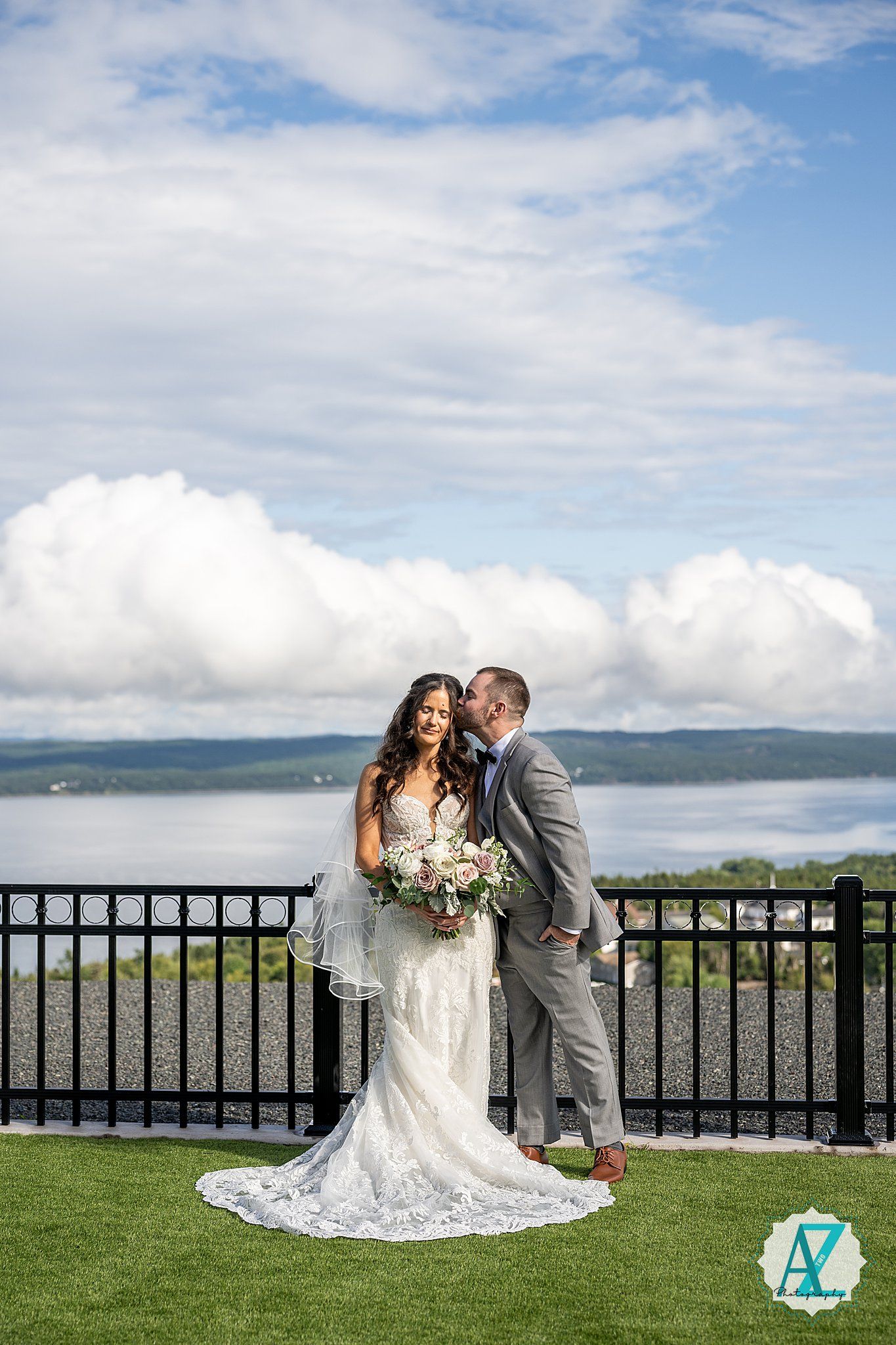 Romantic wedding photoshoot on a scenic overlook with mountains and water in the background on a cloudy day.