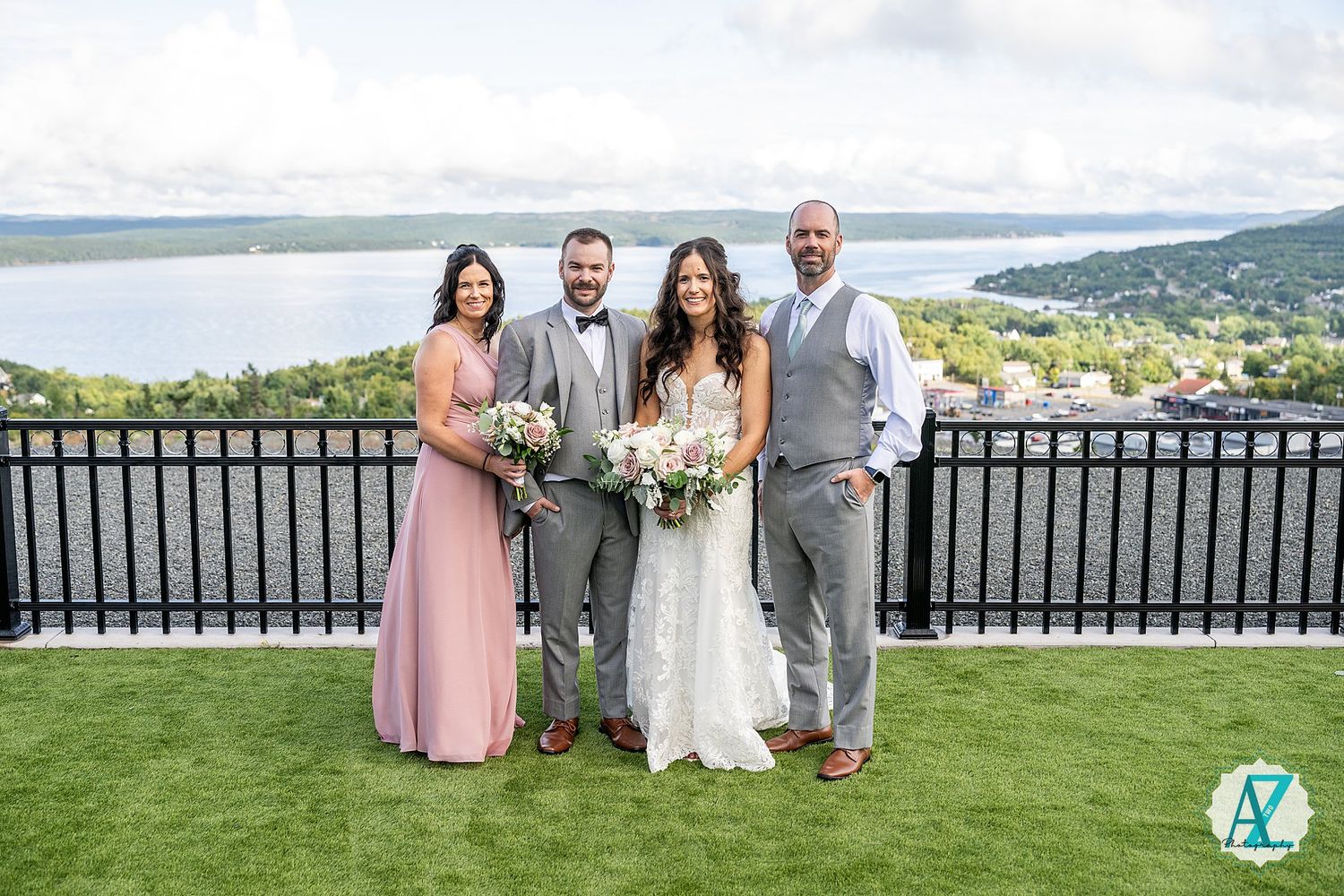 Wedding party members posing on a scenic overlook with mountains and water views in the background.