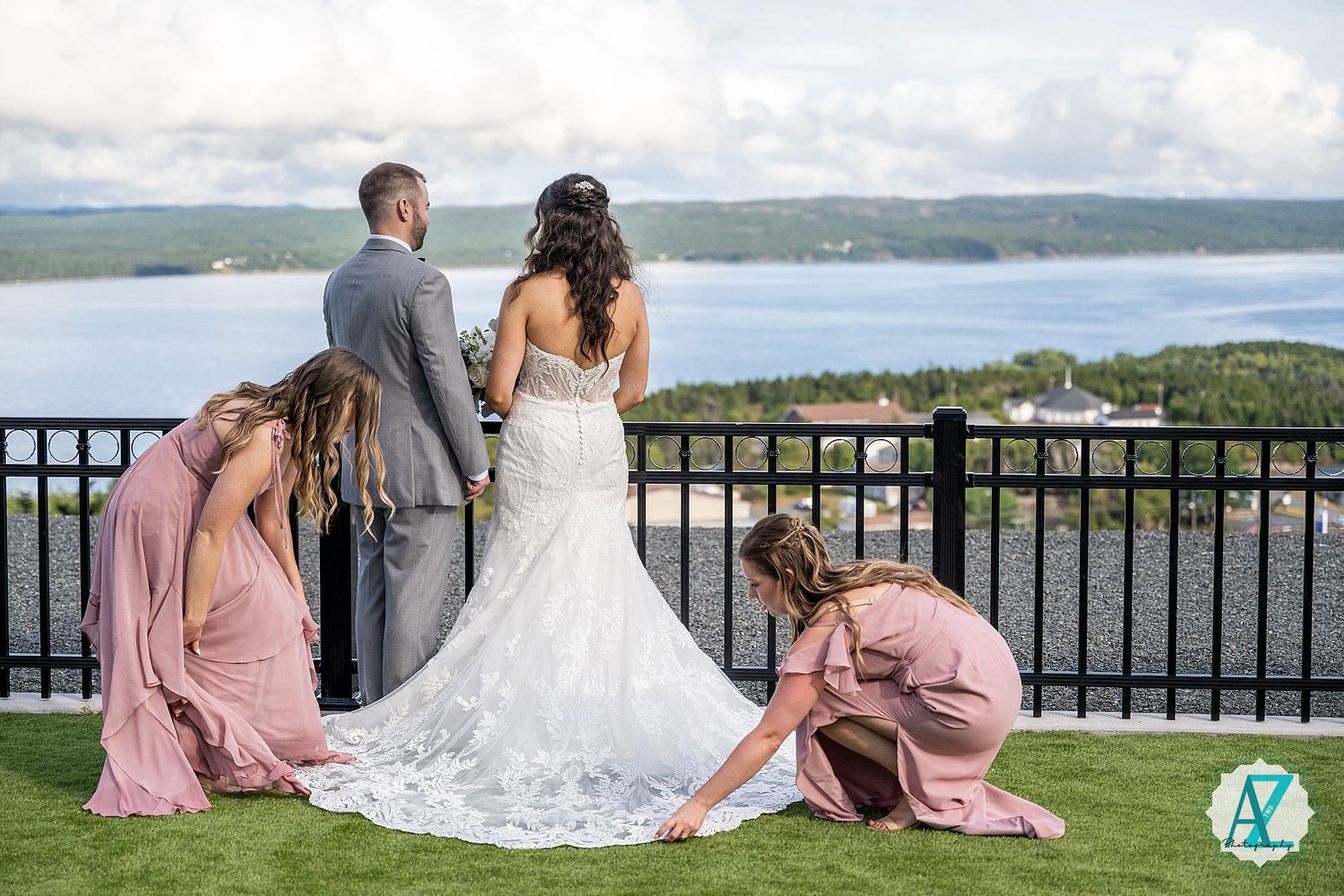 Wedding party gathers on scenic overlook terrace with waterfront views.