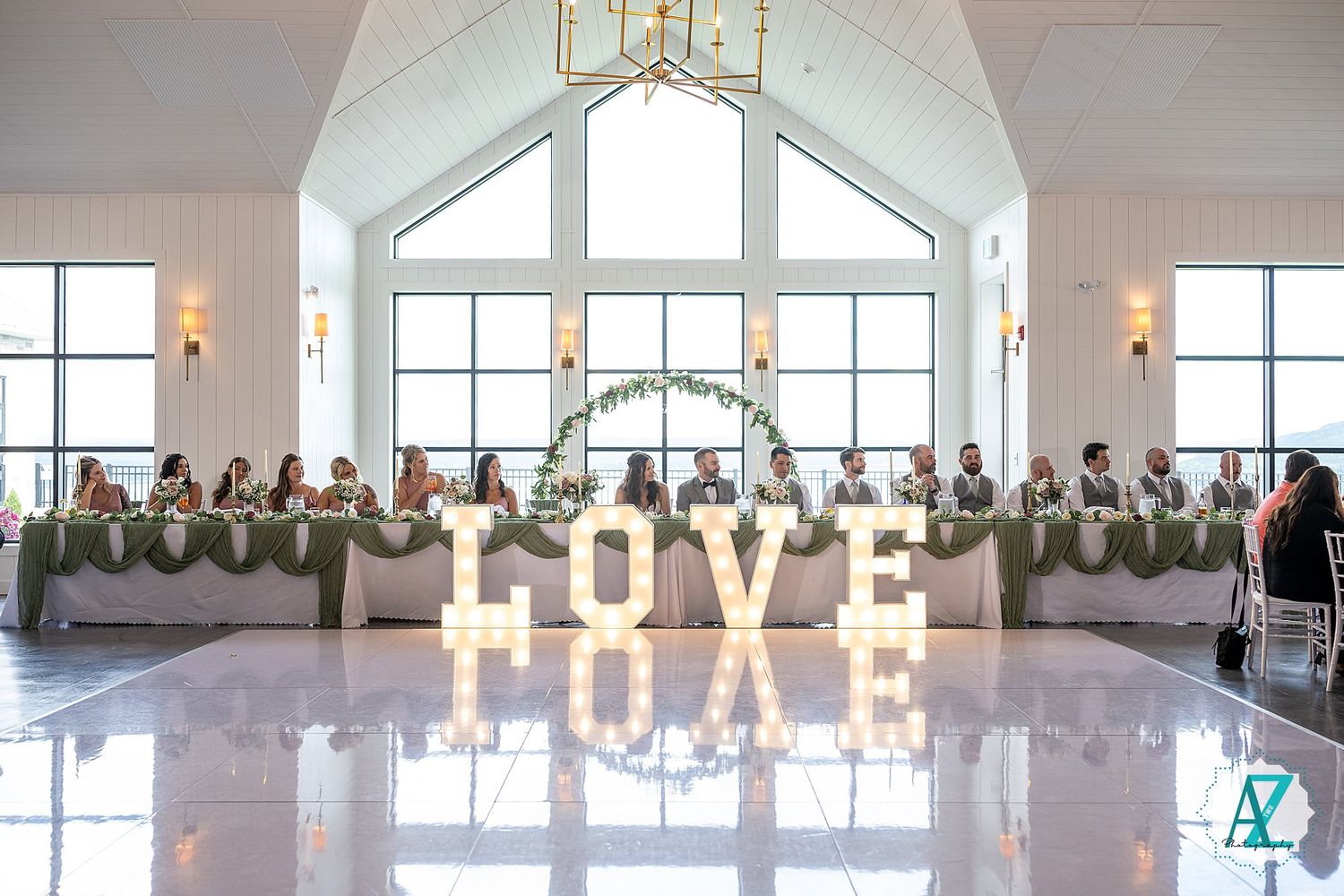Panoramic view of an elegant wedding reception venue with white decor and illuminated LOVE sign.