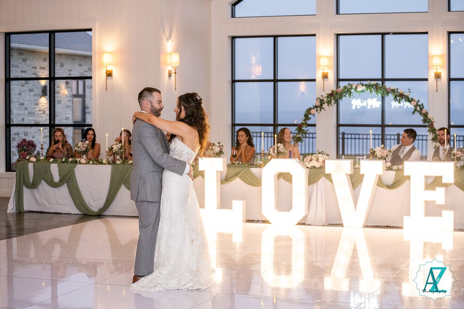 Panoramic view of an elegant wedding reception venue with arched windows, string lights and floral decorations.
