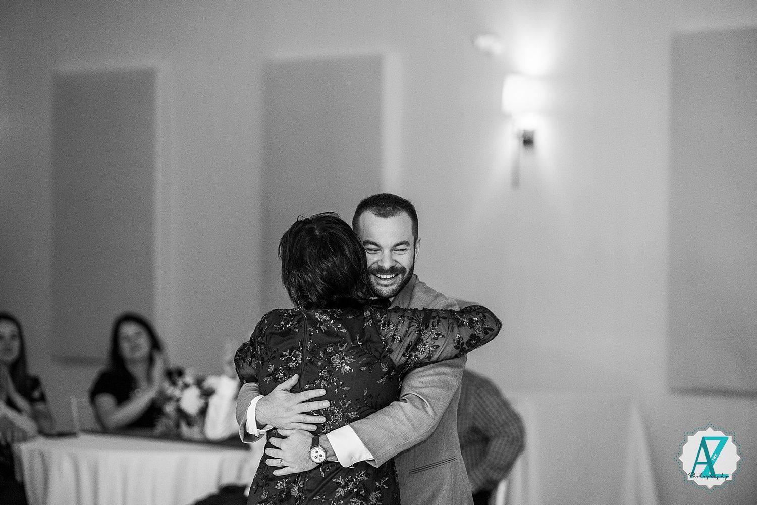 A wedding couple embraces on the dance floor during their first dance at an indoor reception venue.