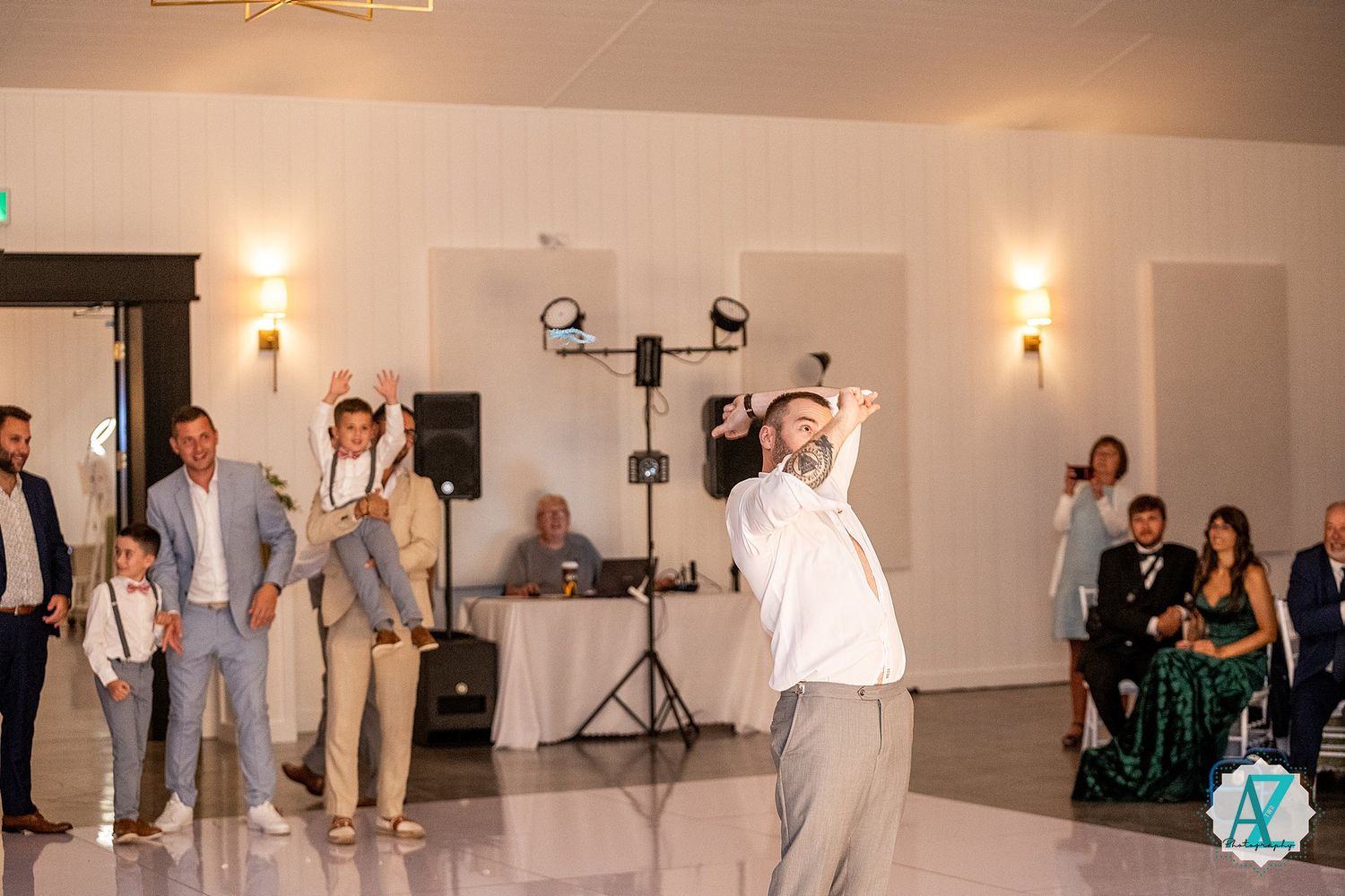 Wedding guests dancing and celebrating together on a dance floor at an indoor reception venue with warm lighting.