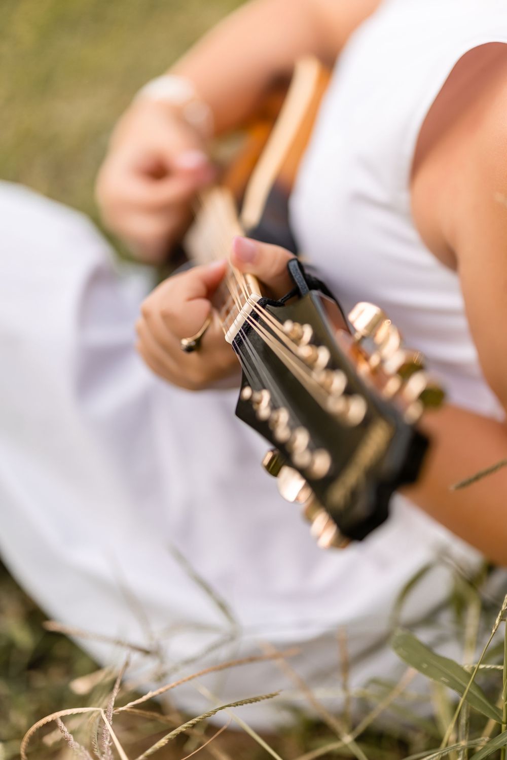 Close-up details of guitar strings and fretboard during outdoor performance.