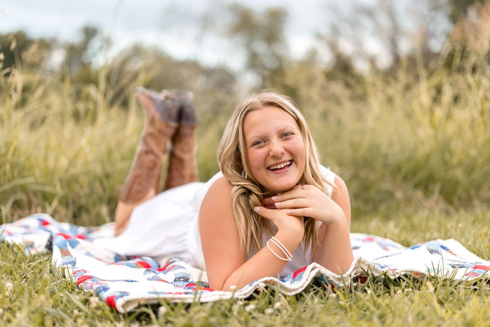 Person relaxing on picnic blanket in sunny meadow during summer photoshoot.